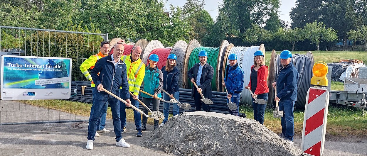 Personen mit Schaufeln vor Kabeltrommeln