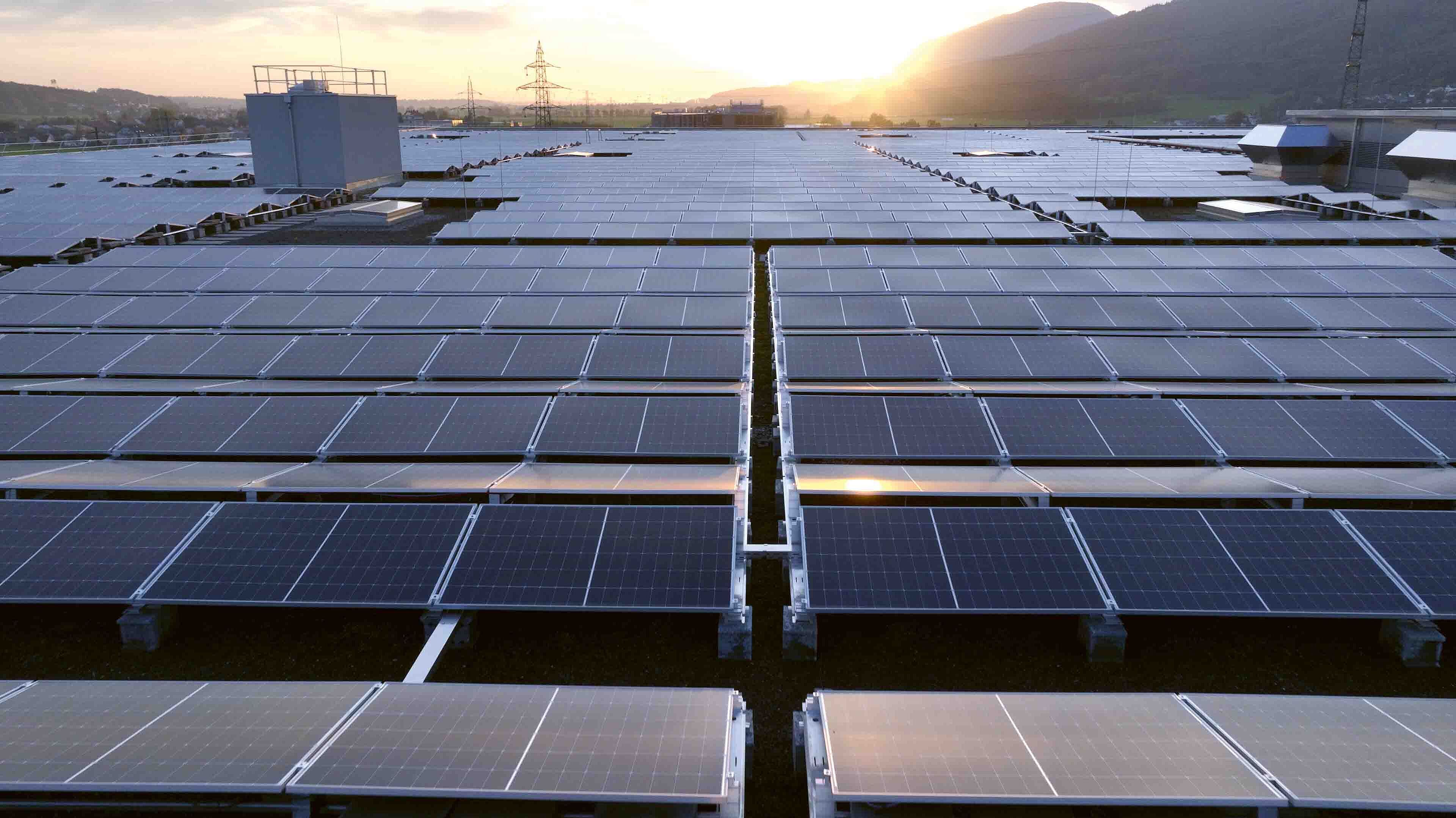 Photovoltaik Anlage auf dem Dach der Migros mit Sonnenuntergang im Hintergrund