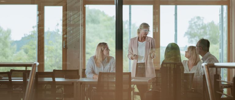 Business Meeting mit 5 Menschen, welches von draußen fotografiert wurde