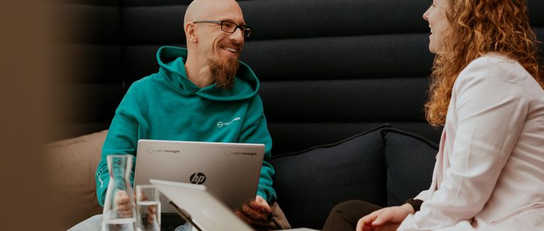 Zwei Mitarbeitende arbeiten zusammen und lachen
