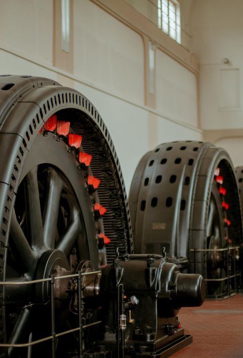 Große Turbinen in einem Wasserkraftwerk, mit roten Akzenten auf den Rädern, in einer geräumigen Halle.